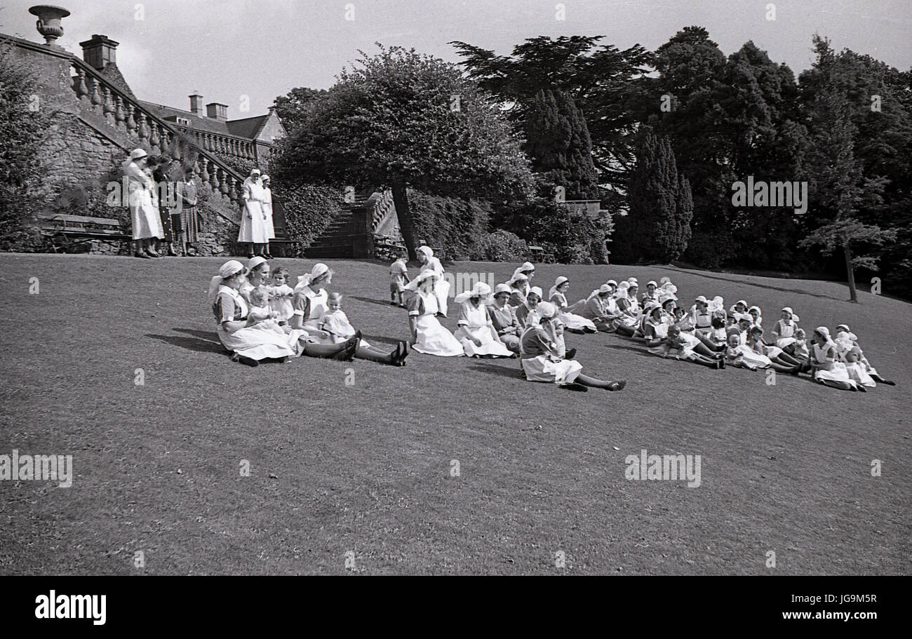 1940, England, wartime, In the grounds of Stanstead Hall, home of Lady Butler (Sydney Courtauld) wife of Rab Butler, Conservative politician, the nurses there who look after the child evacuees from London relax on the grass. Stock Photo