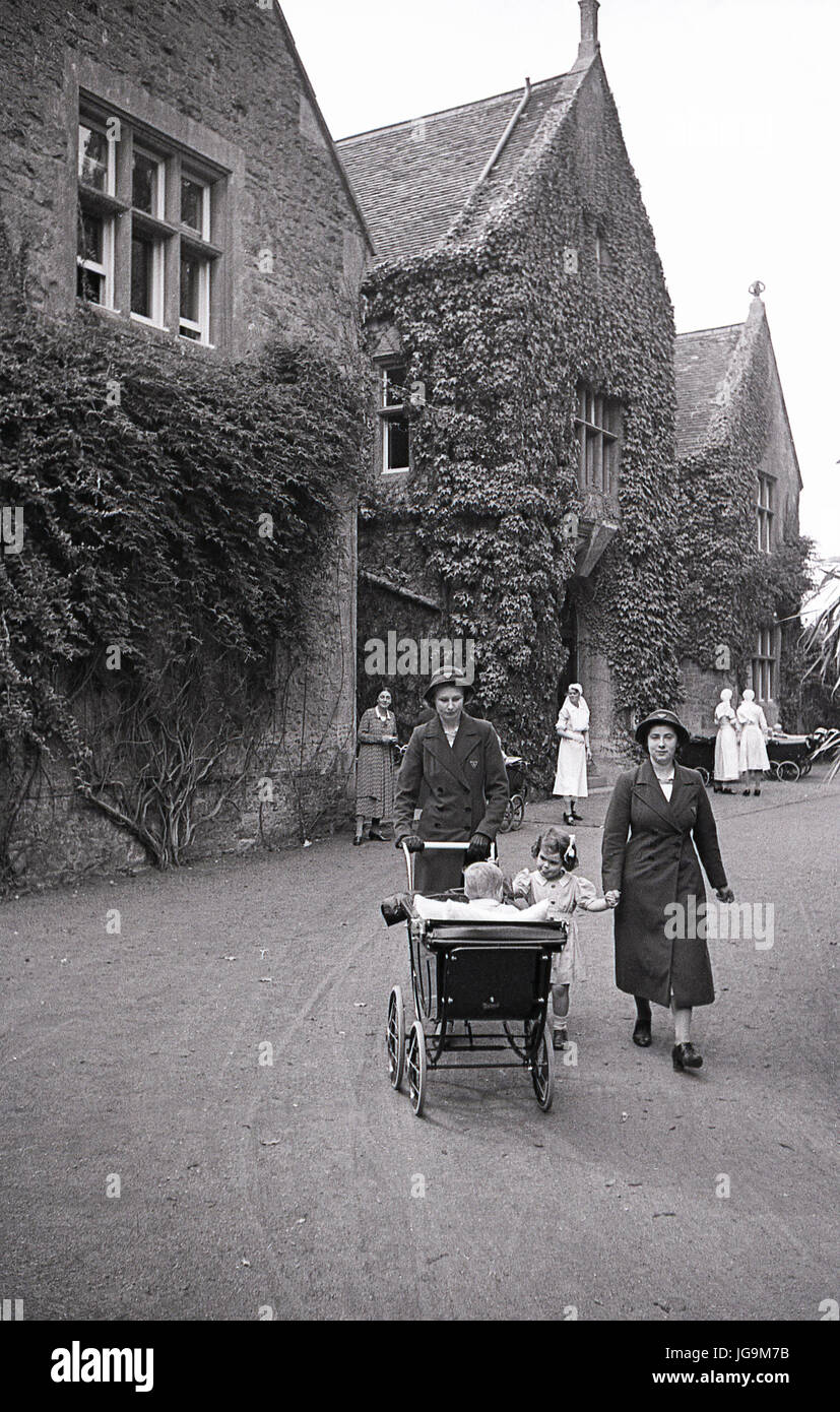 1940s, England, wartime, picture shows the exterior of Stanstead Hall, home of Lady Butler (Sydney Courtauld) wife of Rab Butler, Conservative politiican and minister, two nurses walk a pram in the driveway with evacuated children from Hampstead garden Suburbs, London. Stock Photo