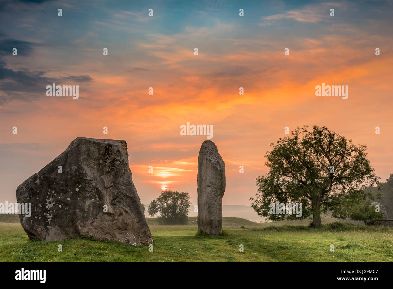 The clouds part as dawn breaks over the ancient Sarsen Stones at Avebury in Wiltshire on the day before the Summer Solstice. Stock Photo