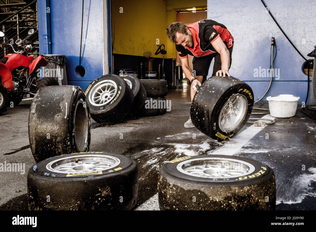 Mechanic working in circuit pit cleaning and washing racing tires set