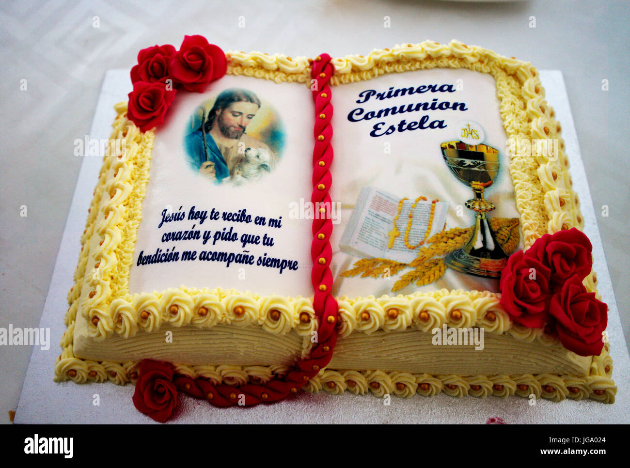 Hand crafted cake for a First Holy Communion celebration with red fondant roses and Spanish language writing Stock Photo