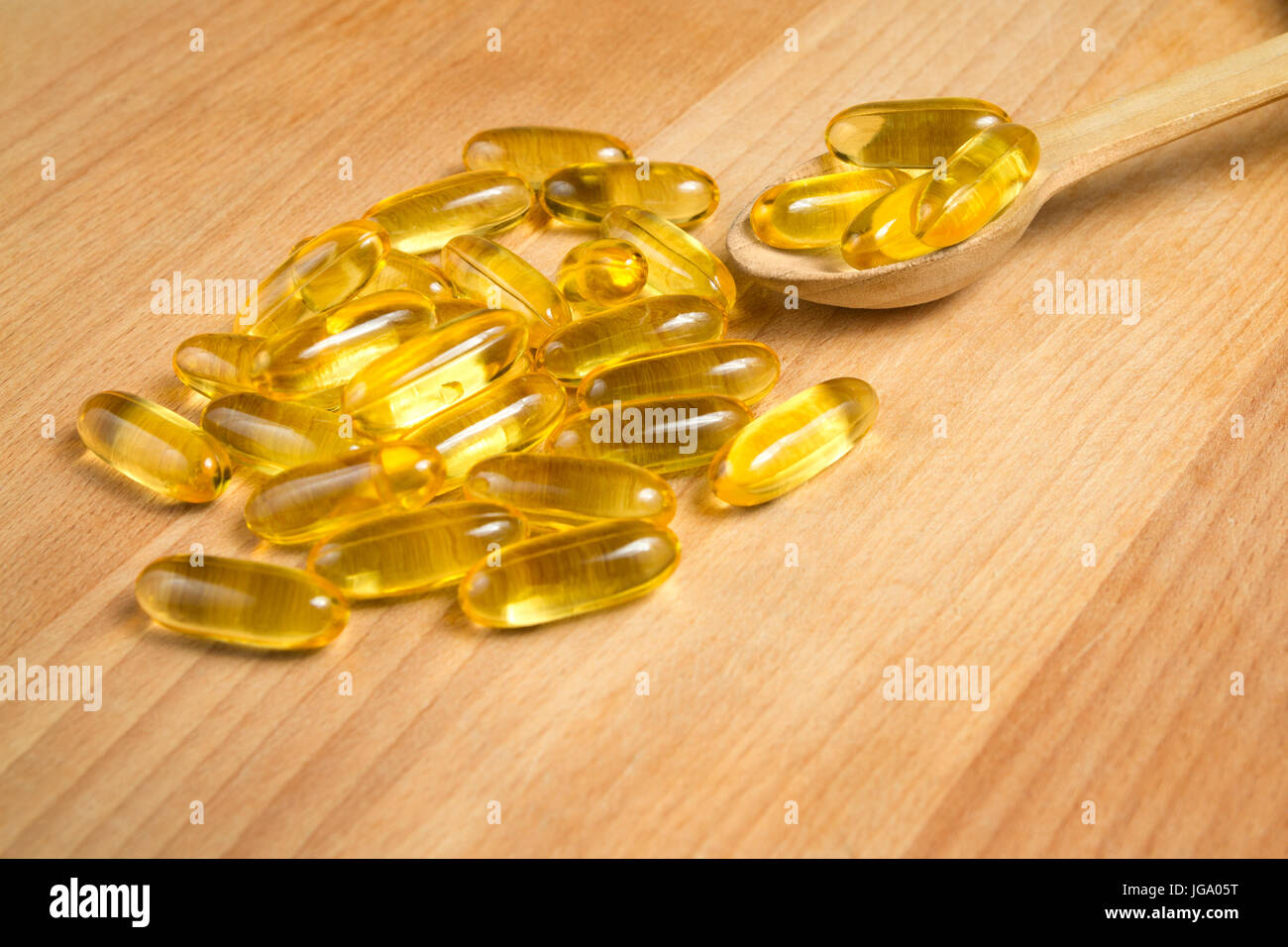 Fish oil gel capsules of omega 3. Close up capsules fish oil in wooden spoon on wooden background. The supplement high vitamin E omega 3 and DHA. Stock Photo