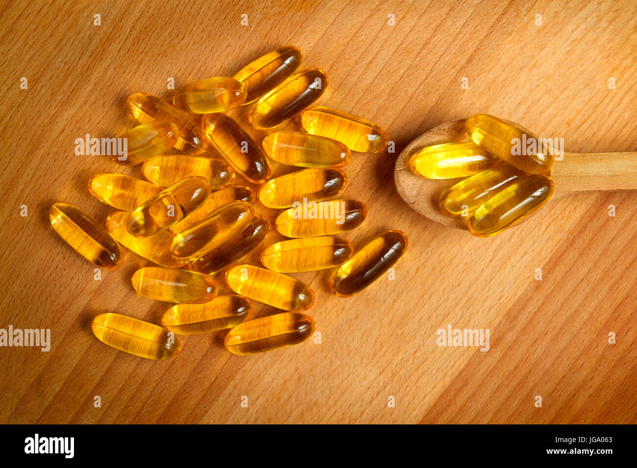 Fish oil gel capsules of omega 3. Close up capsules fish oil in wooden spoon on wooden background. The supplement high vitamin E omega 3 and DHA. Stock Photo