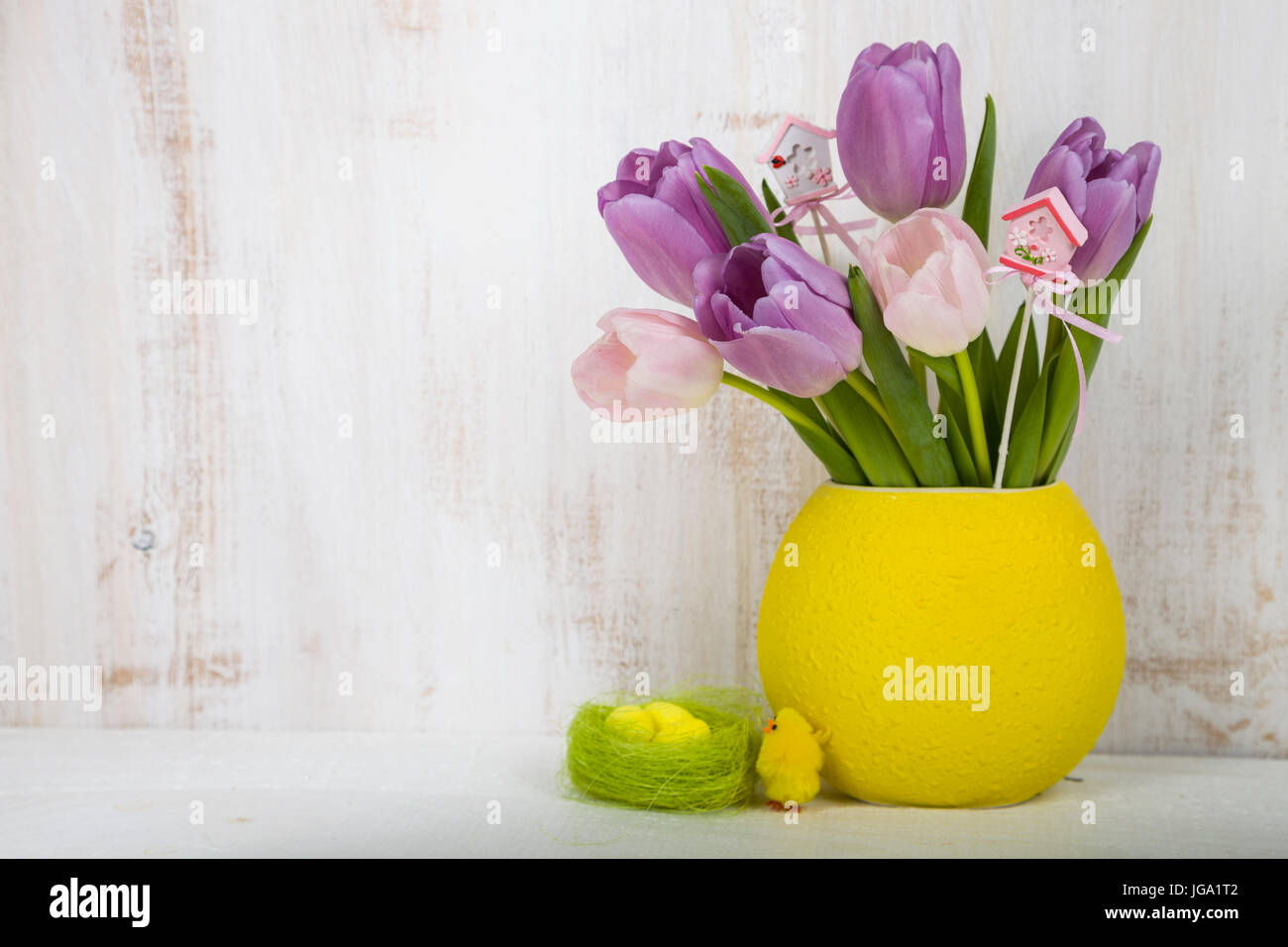 Bouquet purple tulips and Easter eggs on a light wooden table. Easter ...