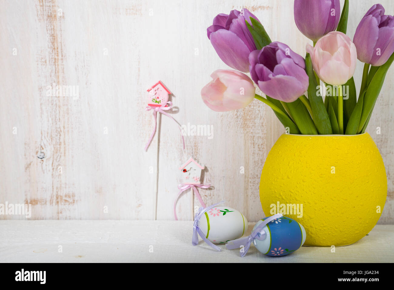 Bouquet purple tulips and Easter eggs on a light wooden table. Easter ...