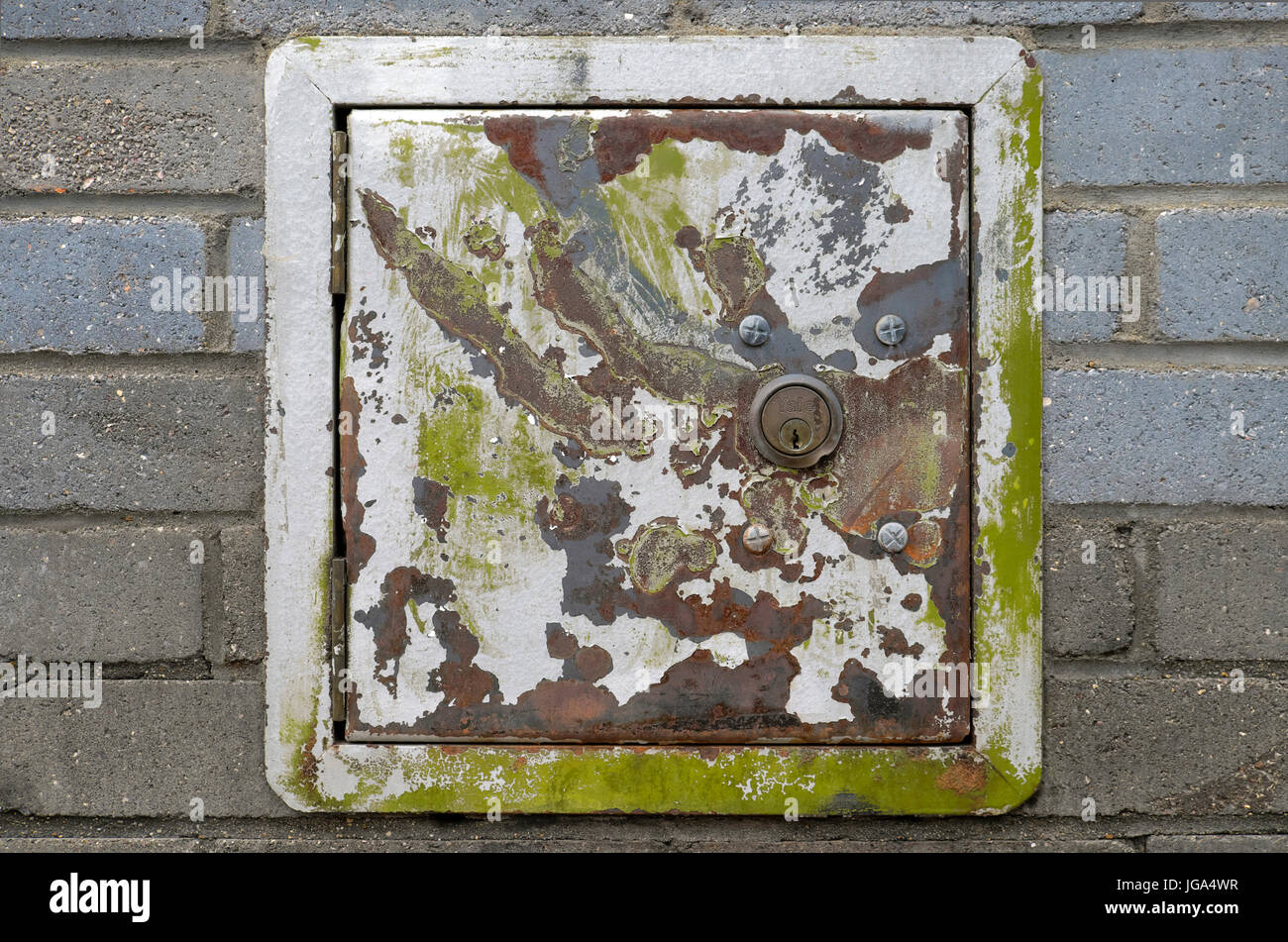 A green and gray paint splattered corroded metal safe box with a lock built into a brick wall in Shoreditch Tower Hamlets East London UK  KATHY DEWITT Stock Photo