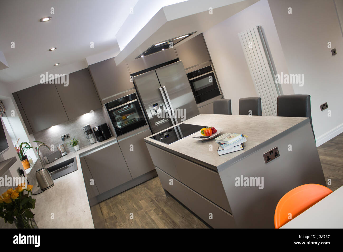 A modern, matt grey kitchen interior showing a centre island with dining stools Stock Photo