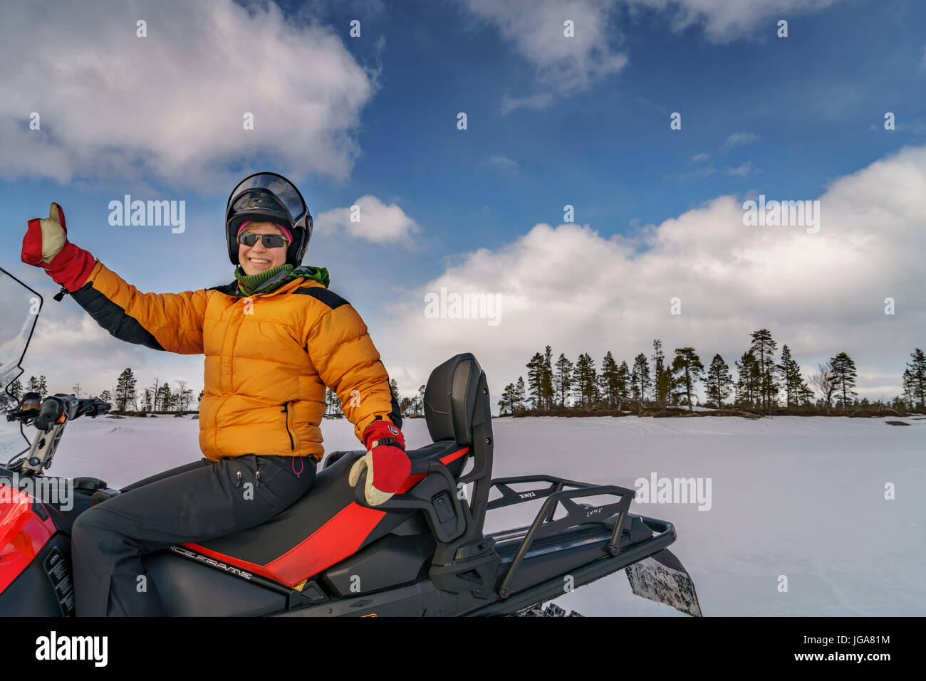 Woman on a snowmobile, thumbs up, Lapland, Finland Stock Photo