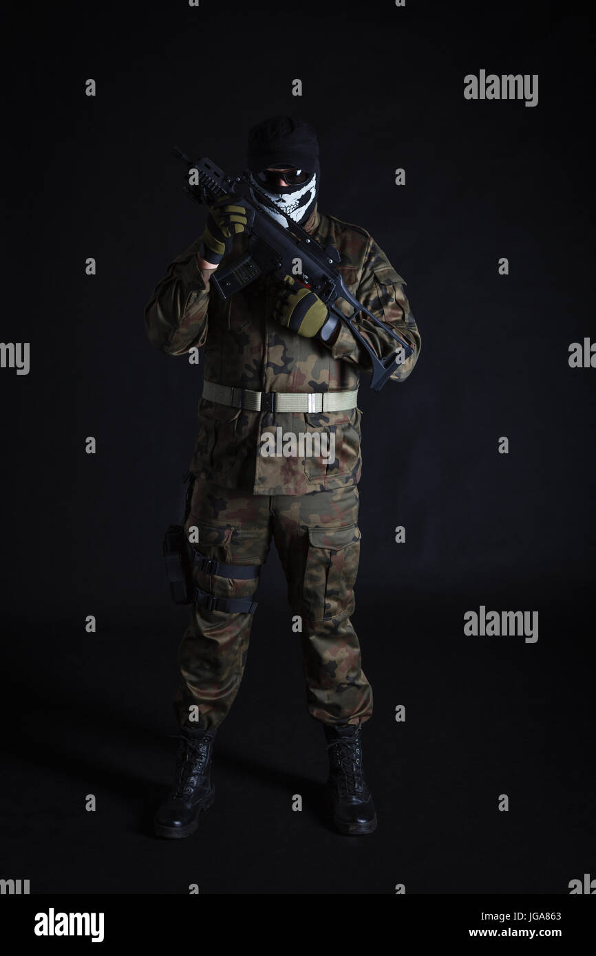 Anti terrorist in black mask holding a gun on black background Stock Photo