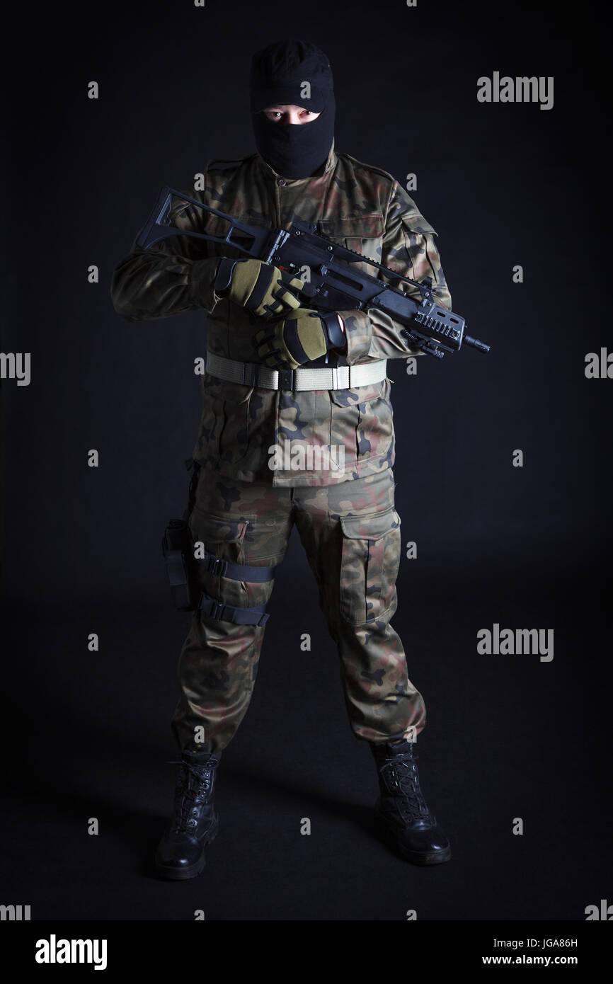 Anti terrorist in black mask holding a gun on black background Stock Photo