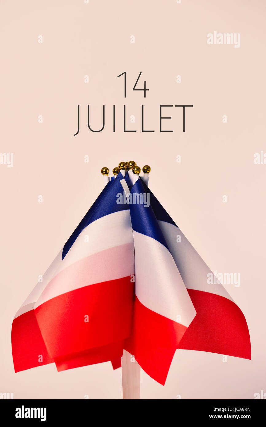 some french flags and the text 14 juillet, 14 july, the national day of France written in French, against an off-white background Stock Photo