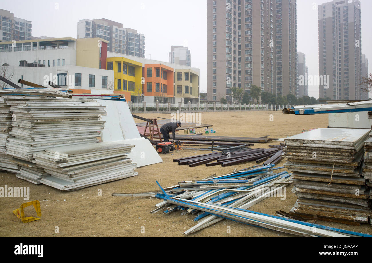 Iron angle bars being cut and erected to support composite fence panels (stacked on ground) around worksite near Han Lin Neighborhood Centre. Suzhou, Stock Photo