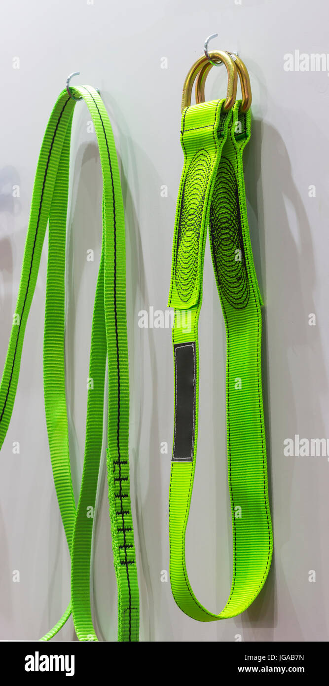 Colorful Cross arm straps hang on a white wall ; safety equipment