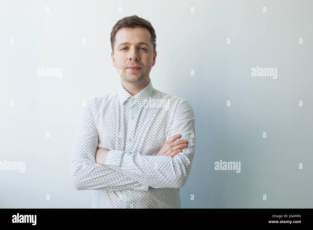 Smiling young man standing with arms crossed Stock Photo - Alamy