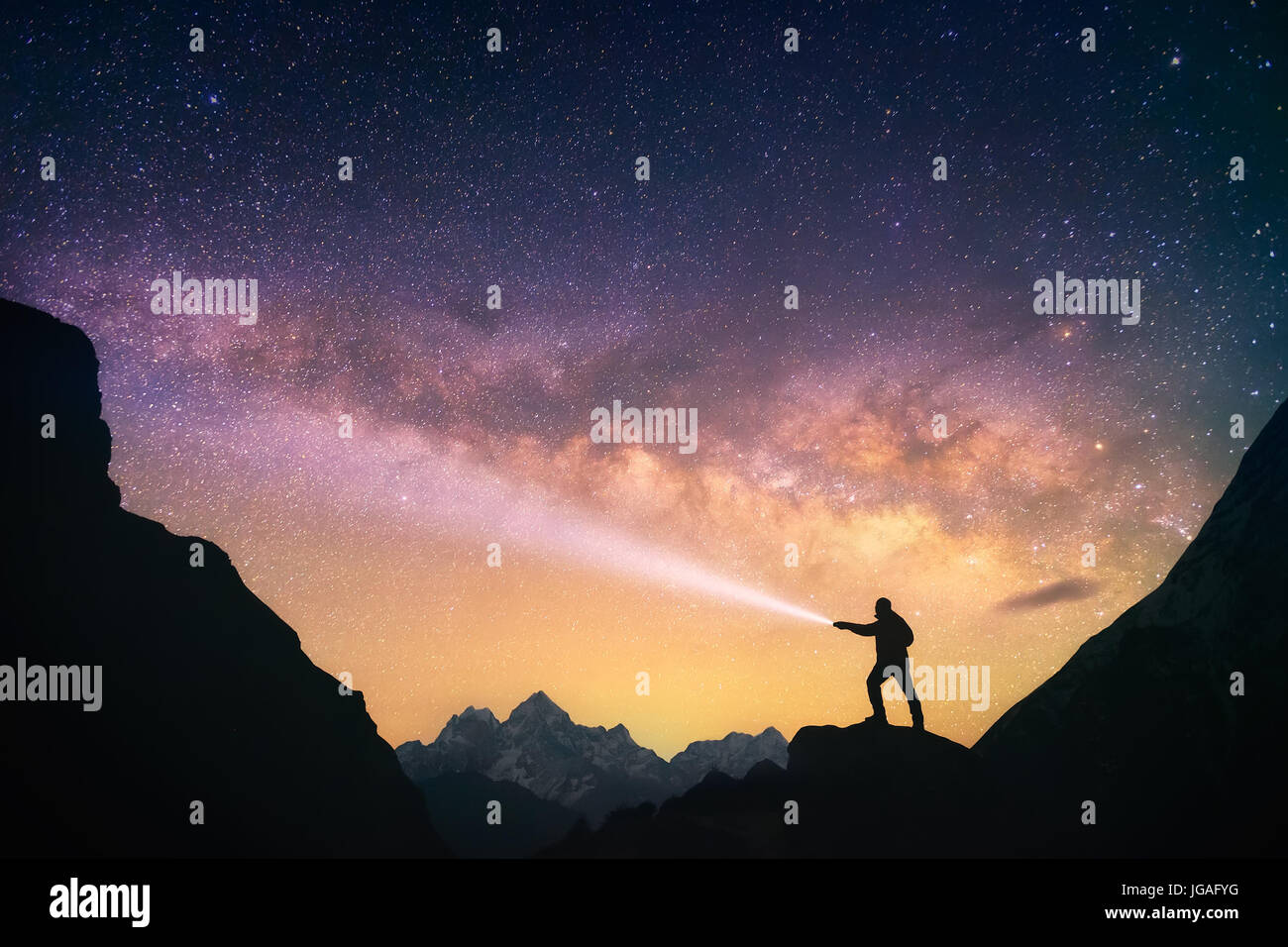 Silhouette of the man standing in the mountains with a flashlight in his hands. Nepal, Everest Region, view of the Mount Thamserku. Stock Photo