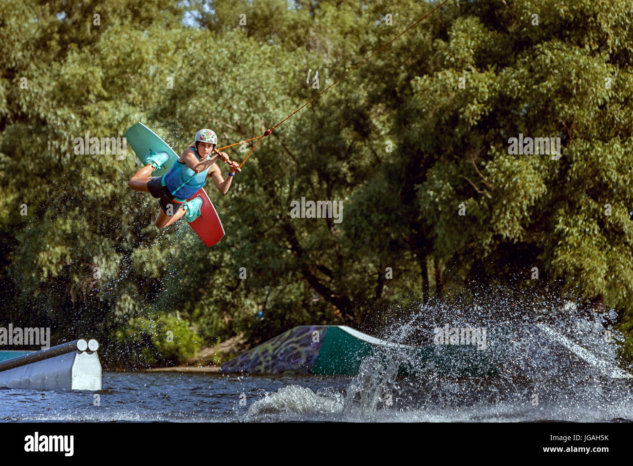 Sports training on a wakeboard. Jumping over water and tricks. Stock Photo