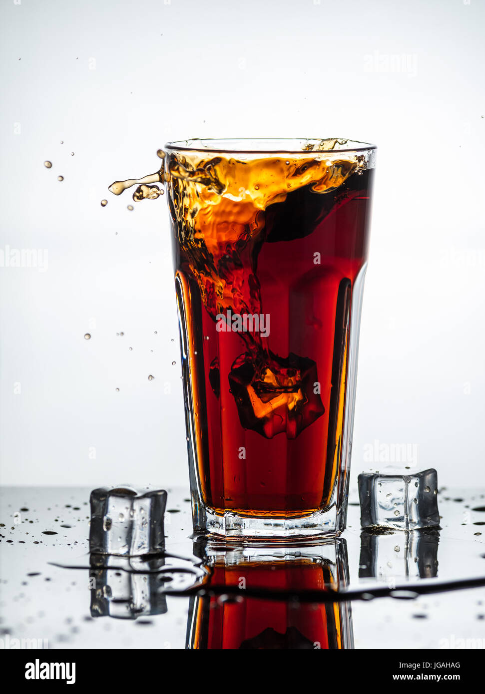 Splashes of drink from a glass with ice cubes Stock Photo - Alamy