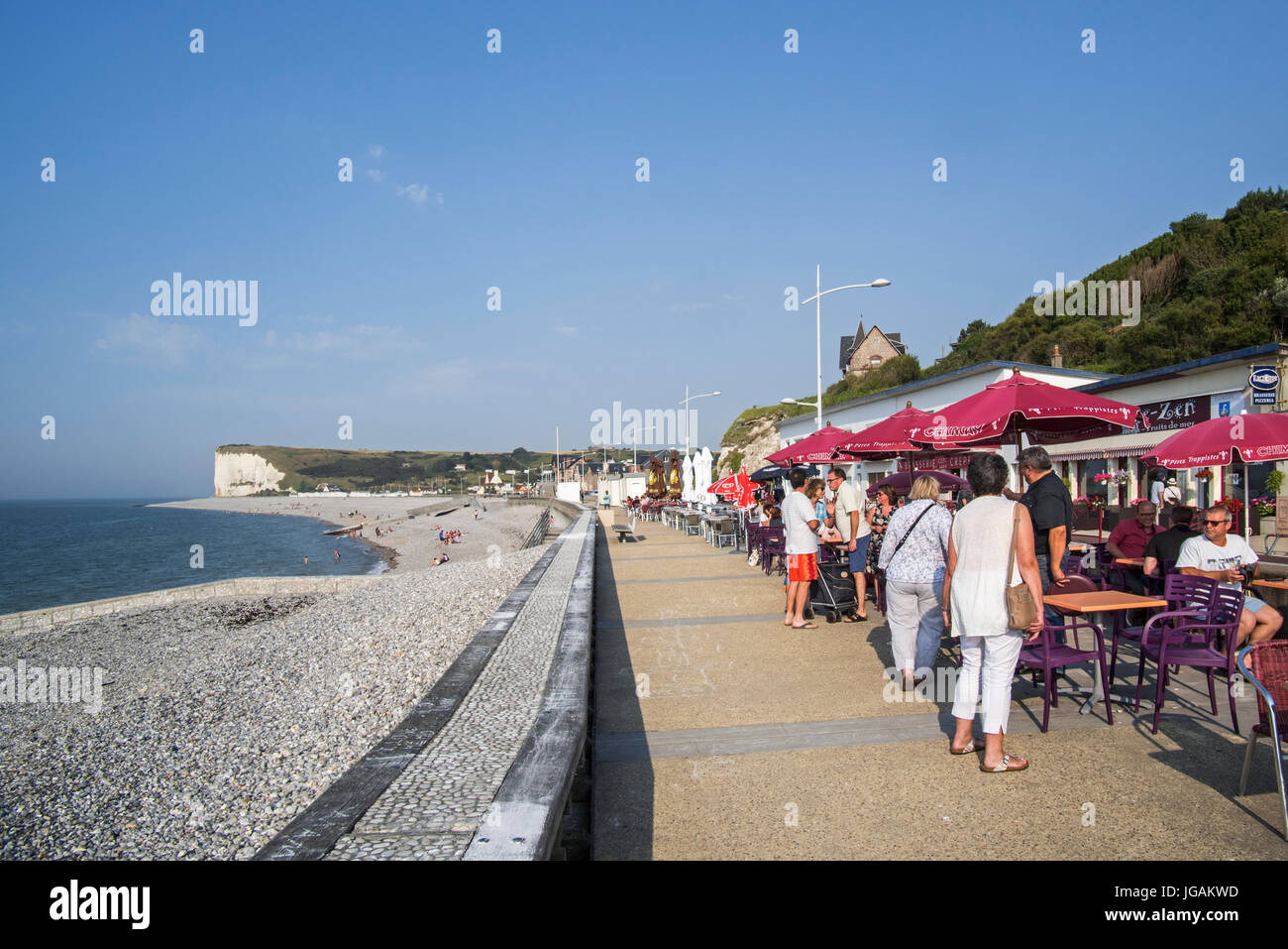Pebble beach and tourists at pavement café on promenade at Veulettes-sur-Mer, Seine-Maritime, Normandy, France Stock Photo