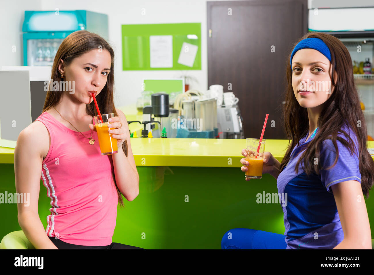Sportive women relaxing over drinks at the gym enjoying a healthy