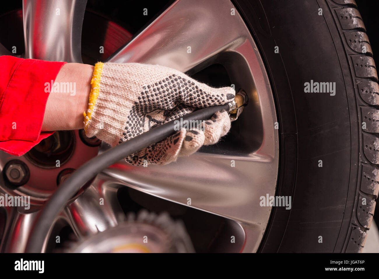 Close up of mechanic's hand checking the air pressure of a tyre in auto ...