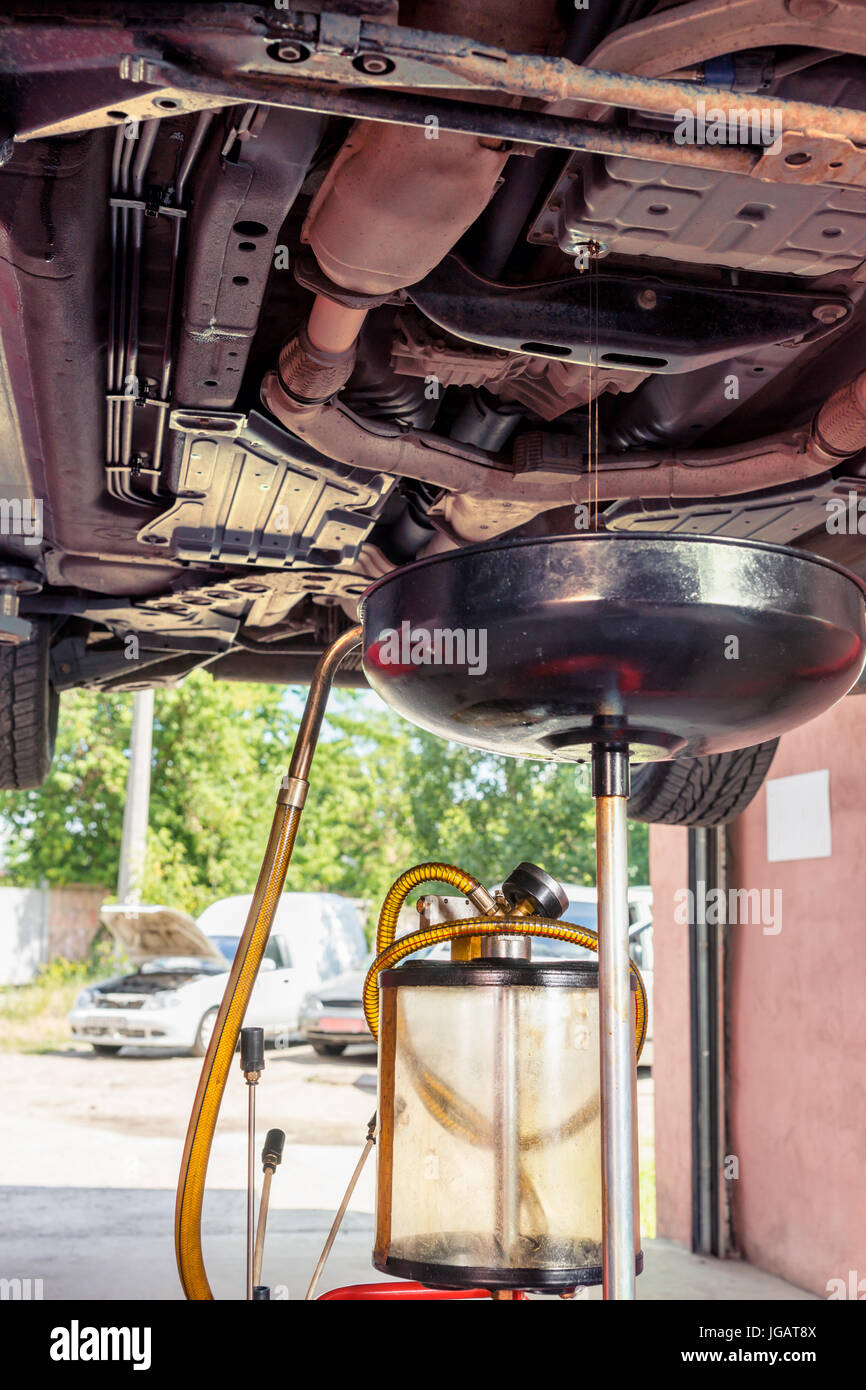 Oil jet flows out into equipment for changing motor oil in automobile engine in a garage Stock Photo