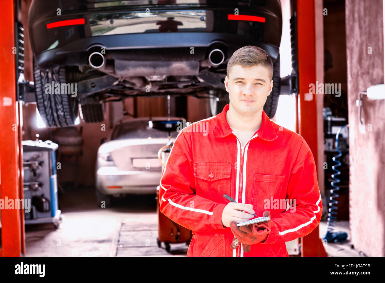 Handsome male motor mechanic standing making notes in front of a black ...