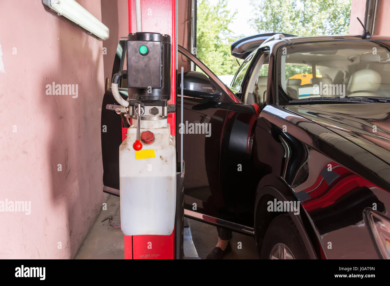 Motor mechanic checking inside a car with a portable programmed computer standing alongside the open door as he performs a service and tune up in a wo Stock Photo