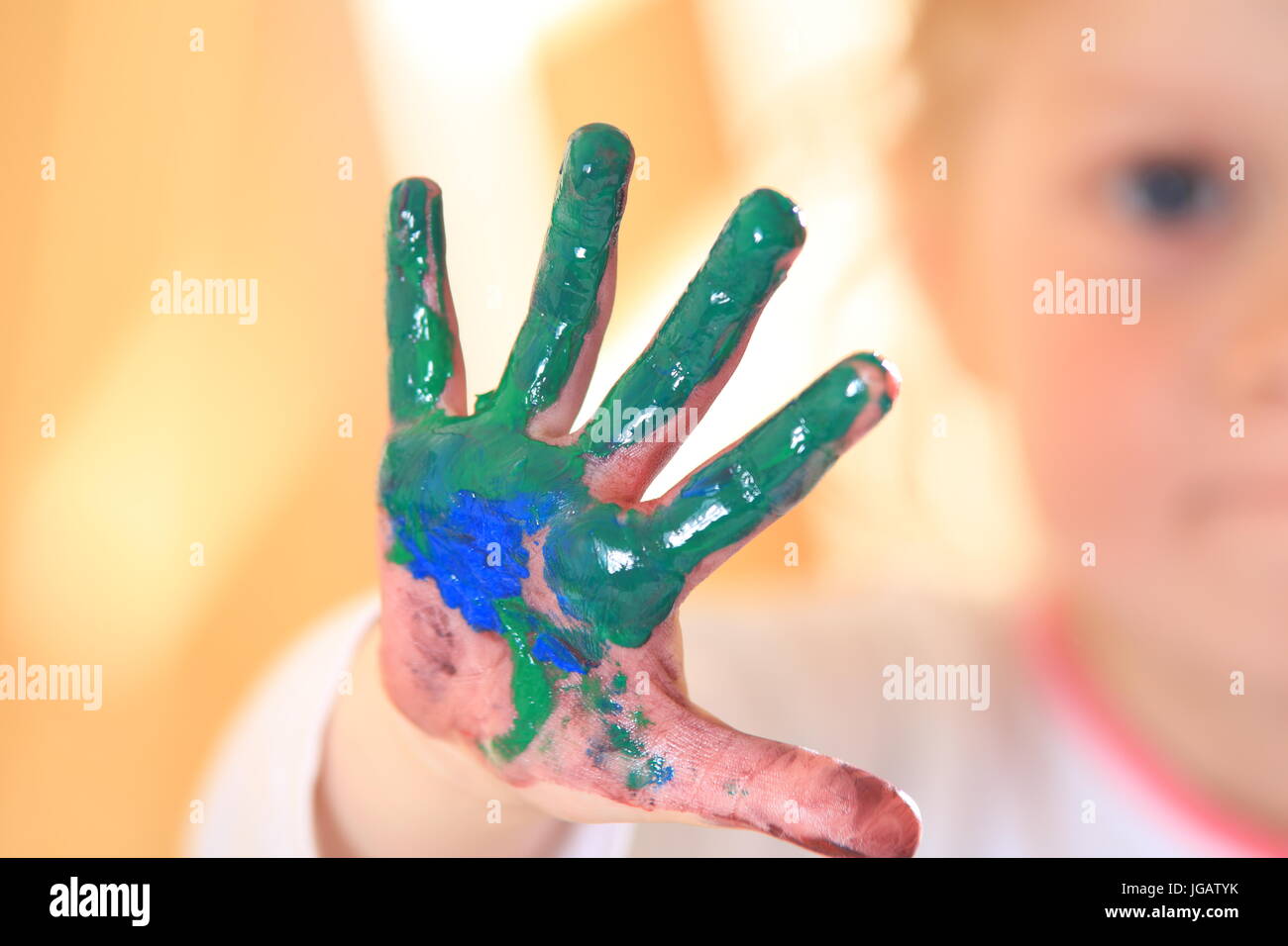 Kid hand in green paint close-up. Dirty child hand after drawing lessons. Stock Photo