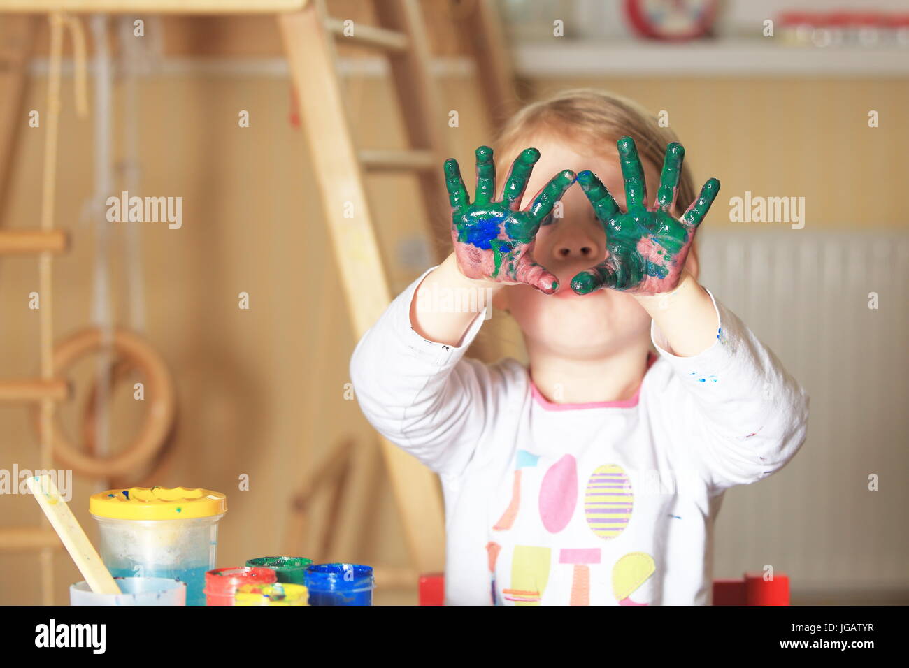 Girl show hands in green paint. Funny theme of children's drawing art. Stock Photo