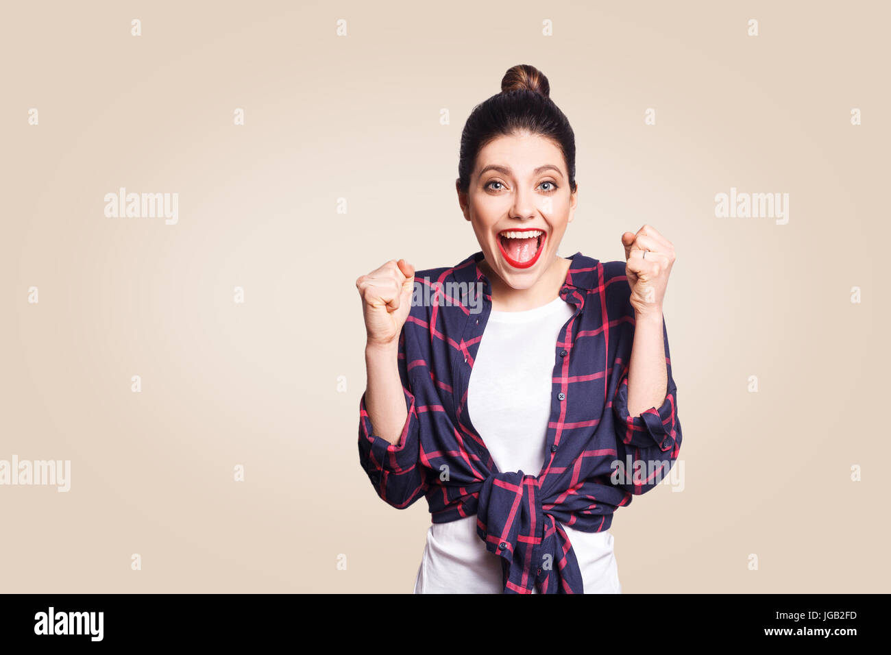 surprised portrait of happy winner ecstatic young woman with casual style having shocked look, exclaiming, keeping mouth wide open and fists clenched  Stock Photo