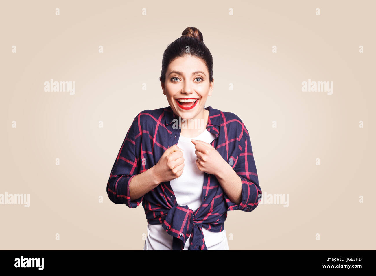 Happy excited young woman with black bun hair screaming or exclaiming, opening mouth widely, gesturing with hands, looking shocked after winning for t Stock Photo