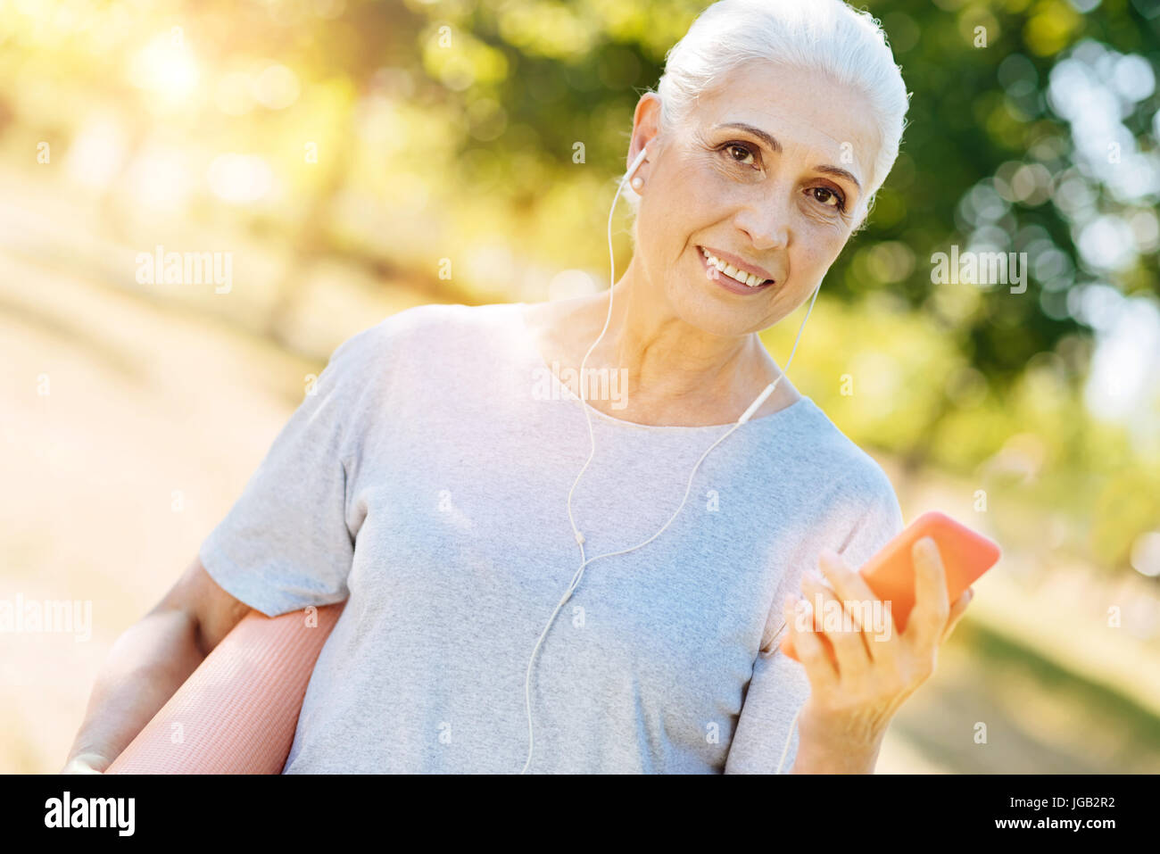Cheerful aged woman listening to music outdoors Stock Photo