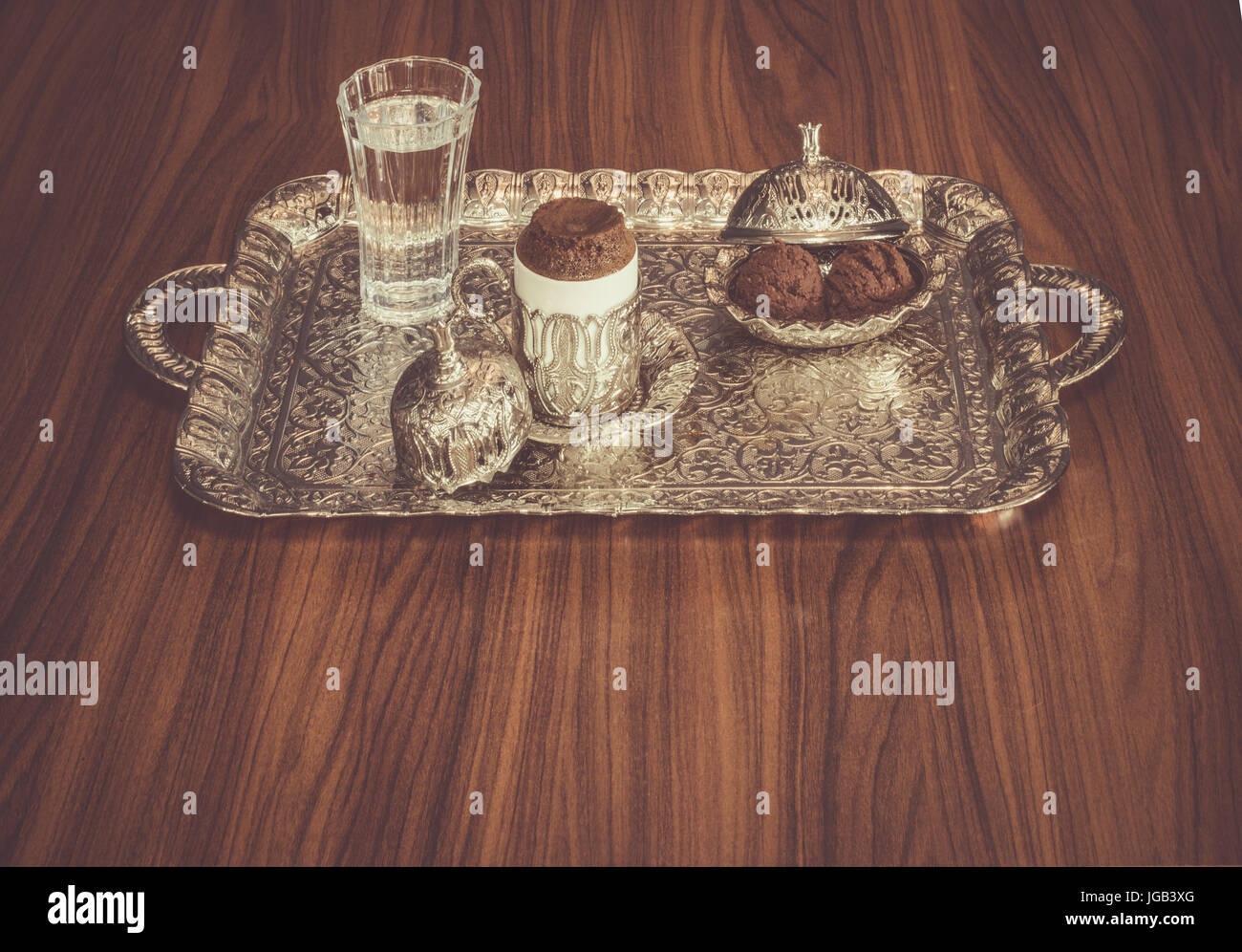 Turkish coffee served with water and cookies on a traditional copper serving set Stock Photo