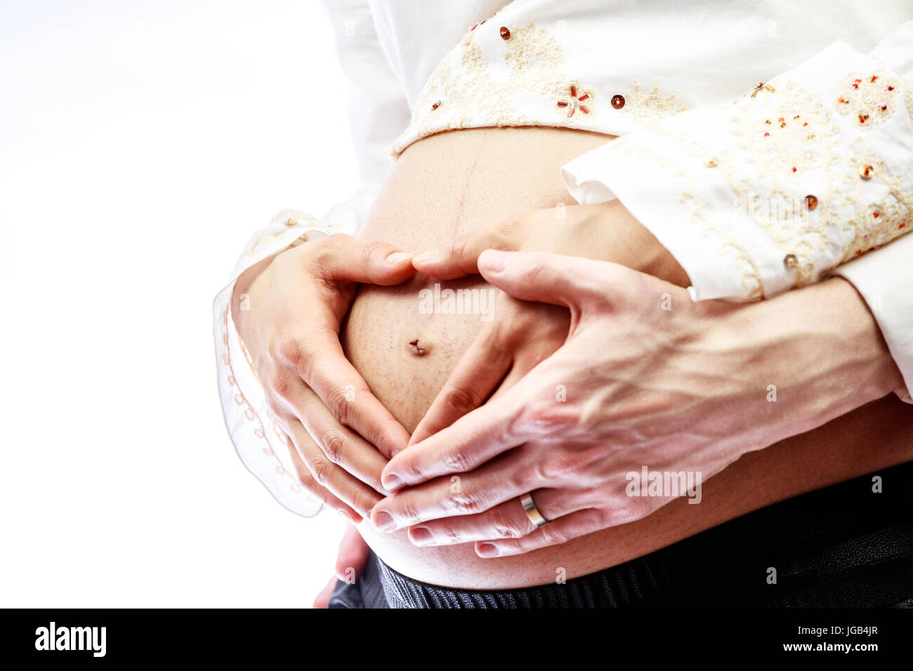 Mom and dad creating heart shape on pregnant belly Stock Photo