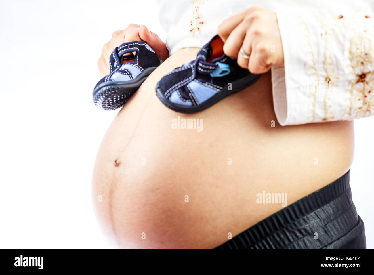 Pregnant woman with cute, small shoes for the baby on her belly. Stock Photo