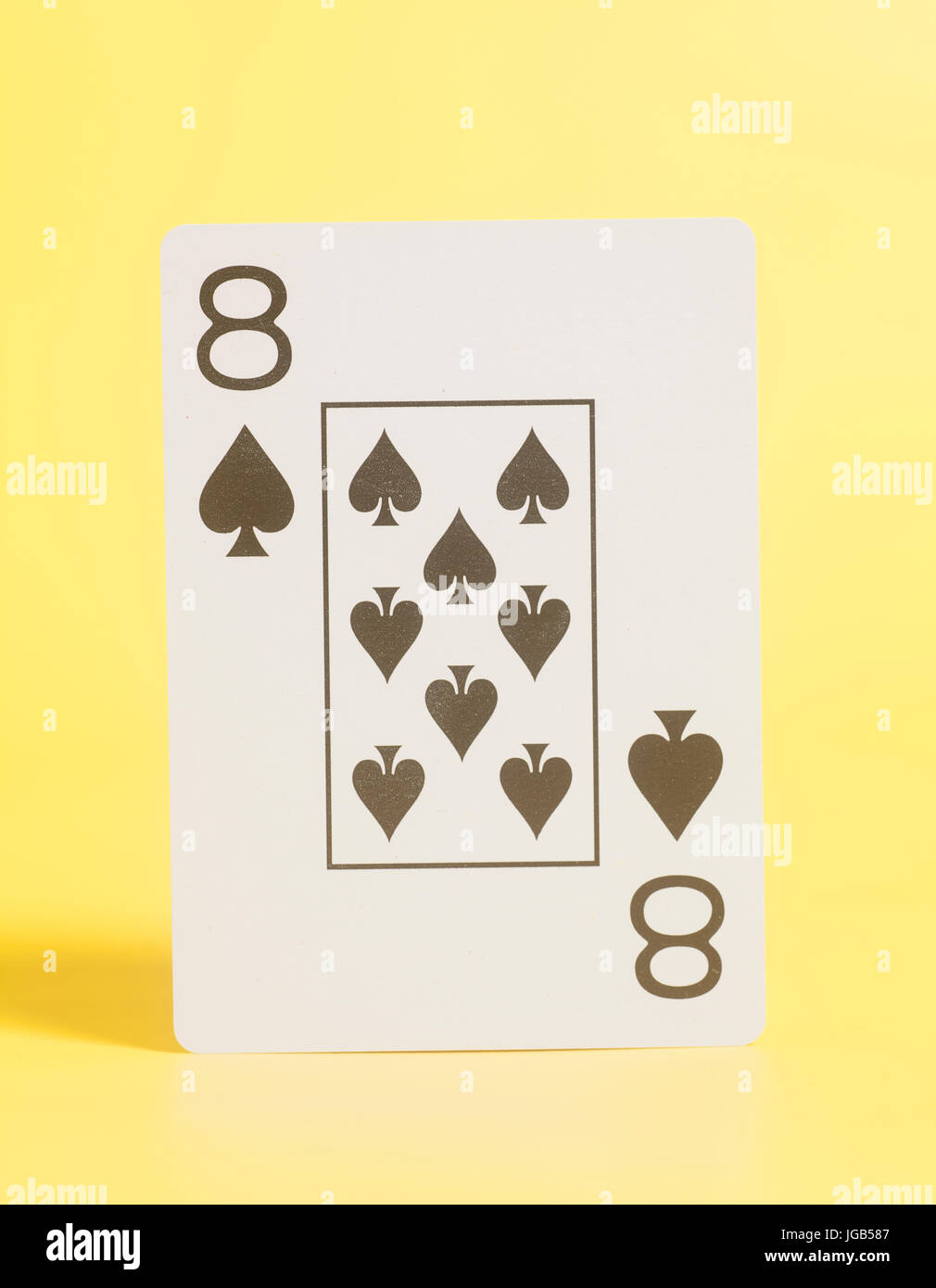 Playing card eight of spades on yellow background Stock Photo