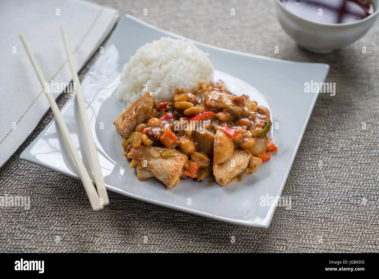 Plate of Kung Pao Chicken on white plate with chopsticks. Stock Photo