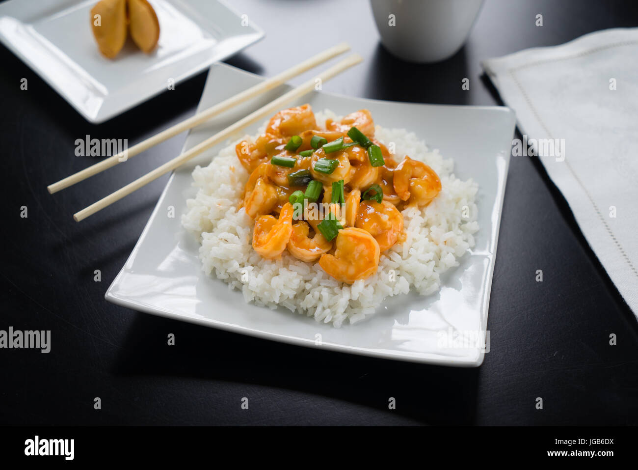 Szechuan Shrimp and rice with green onions on white plate with chopsticks. Stock Photo