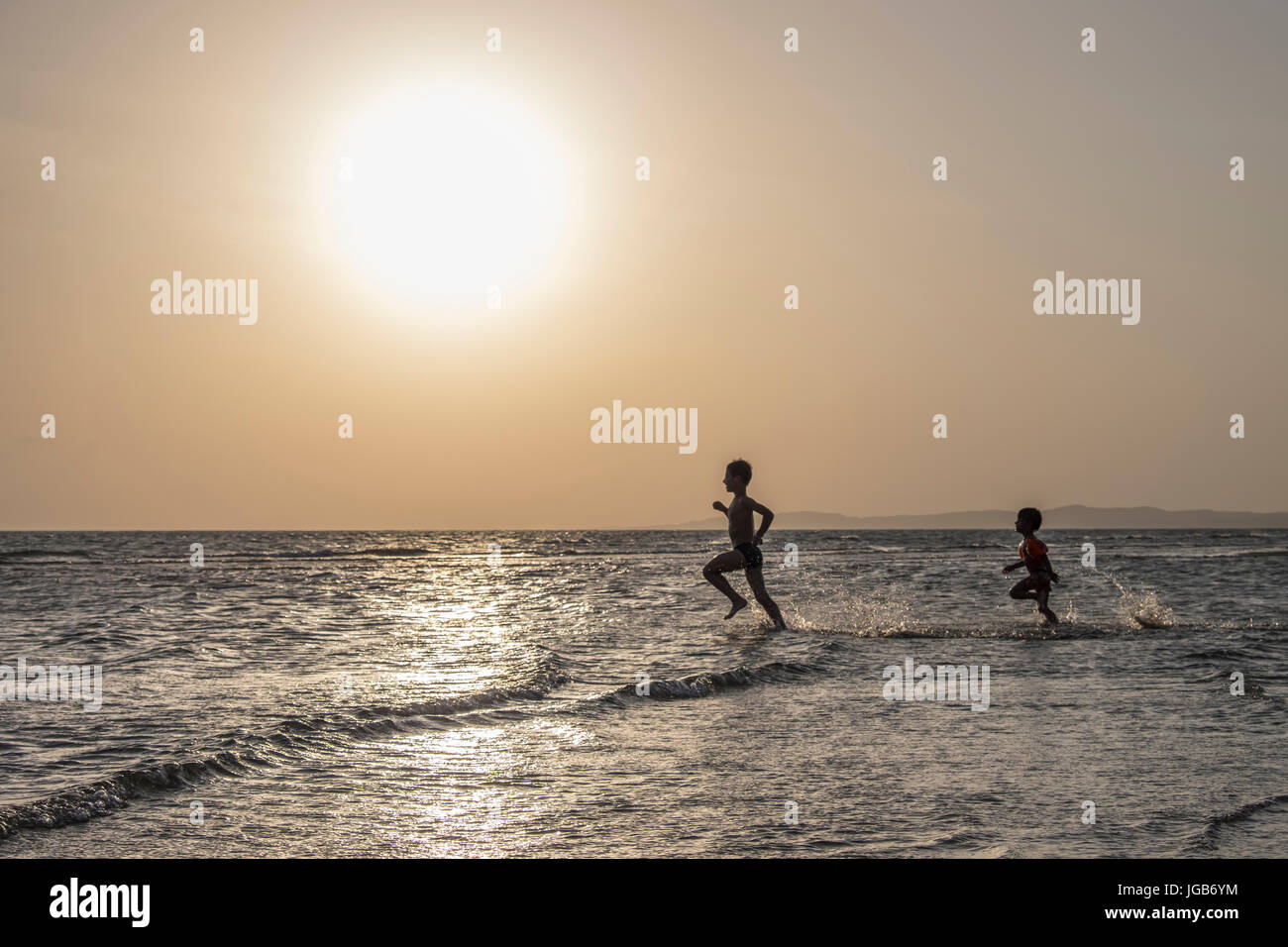 Brothers running with joy on the water. Stock Photo