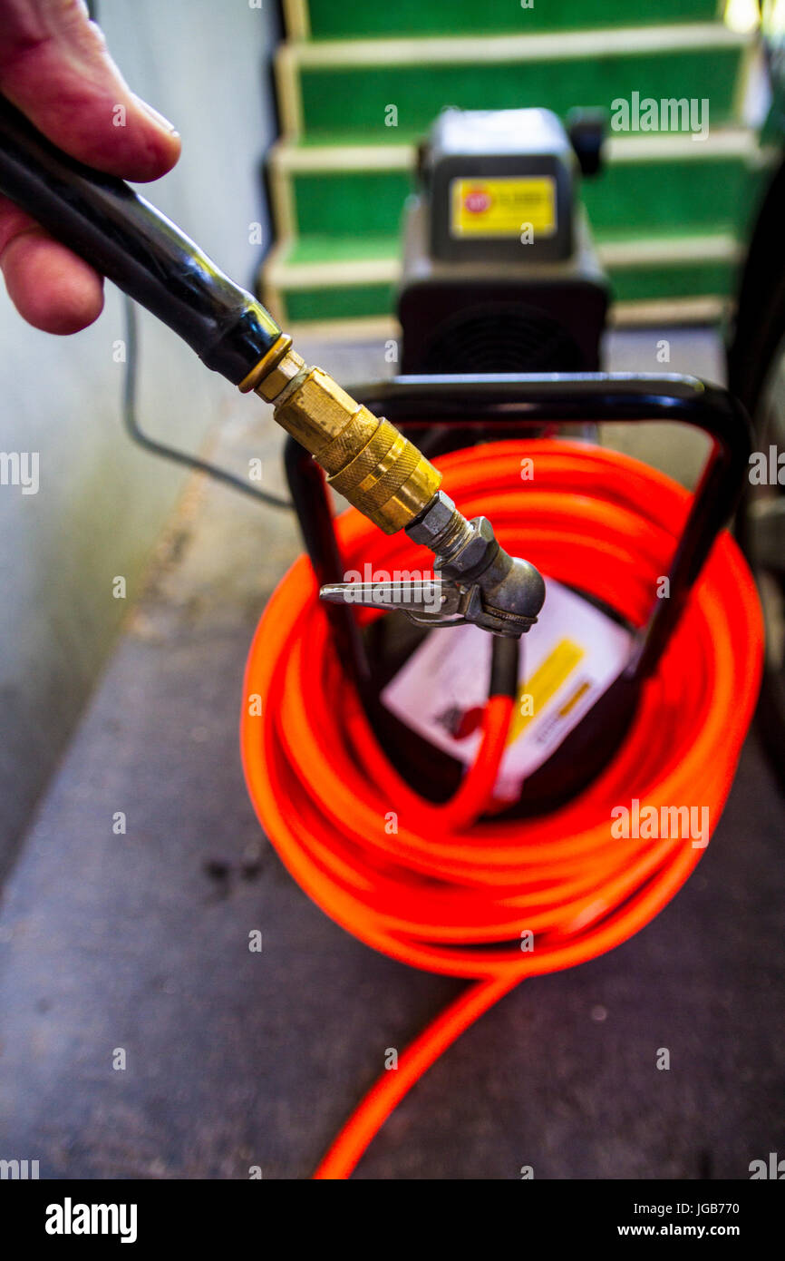 An Air compressor and hose ready to fill a tire with air Stock Photo