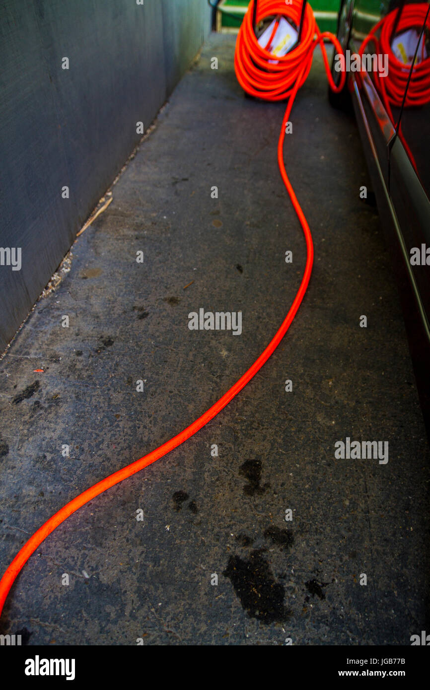 An Air compressor and hose ready to fill a tire with air Stock Photo