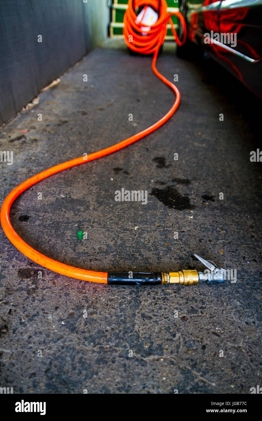 An Air compressor and hose ready to fill a tire with air Stock Photo