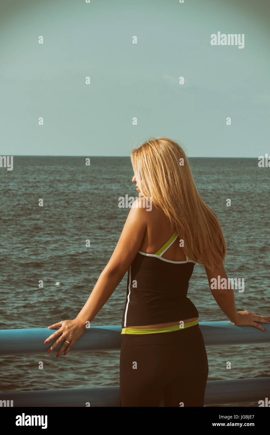 Rear view of a blond woman standing by the sea Stock Photo - Alamy