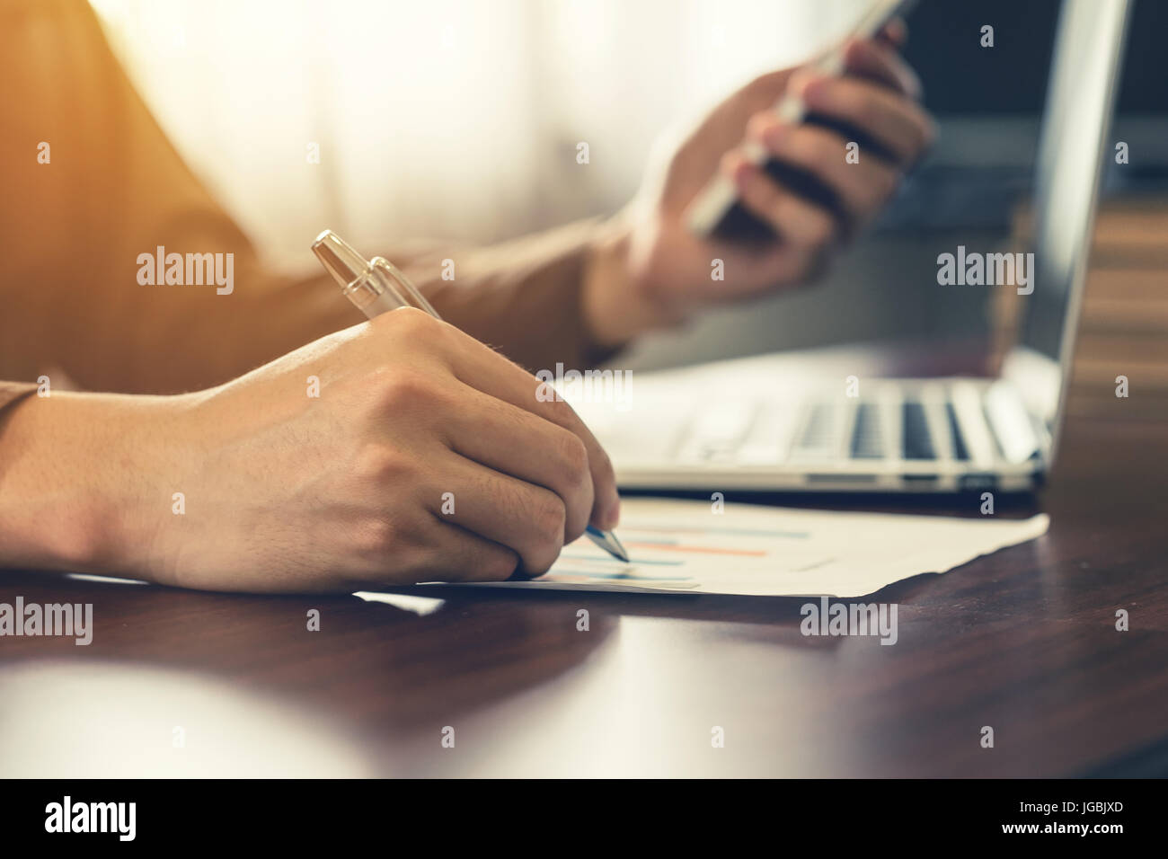 Business man hand writing and holding phone in office. Stock Photo