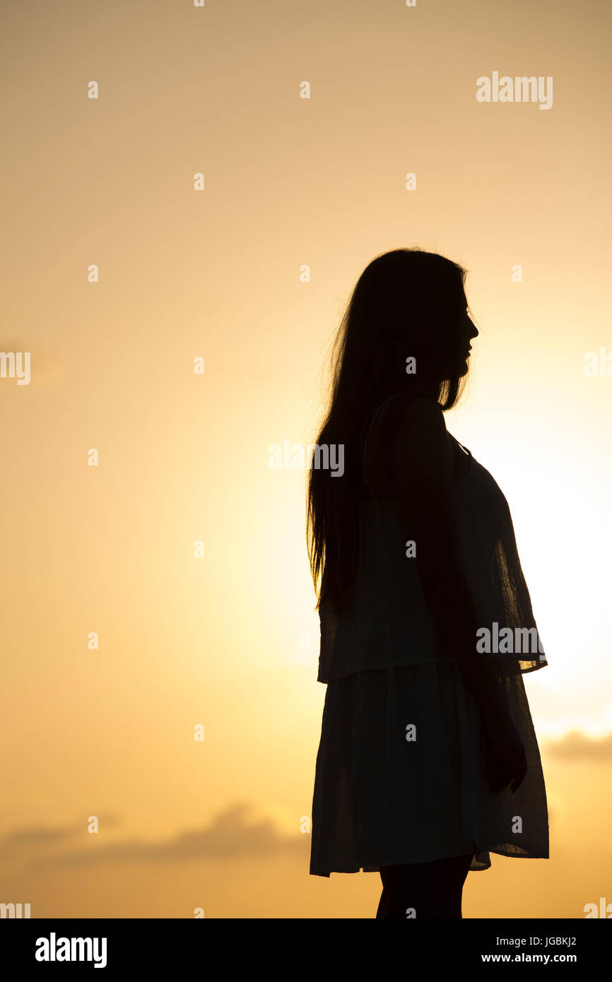 Side view silhouette of a woman standing outdoors at sunsetr Stock Photo