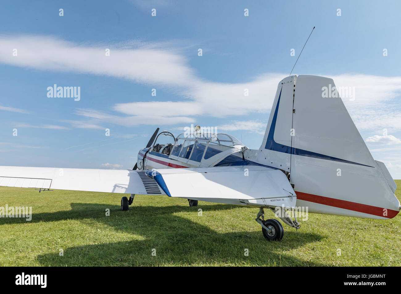 Two seat single engine civil utility aircraft, white small plane, red and blue strip is towed by a glider on a sunny day. Stock Photo