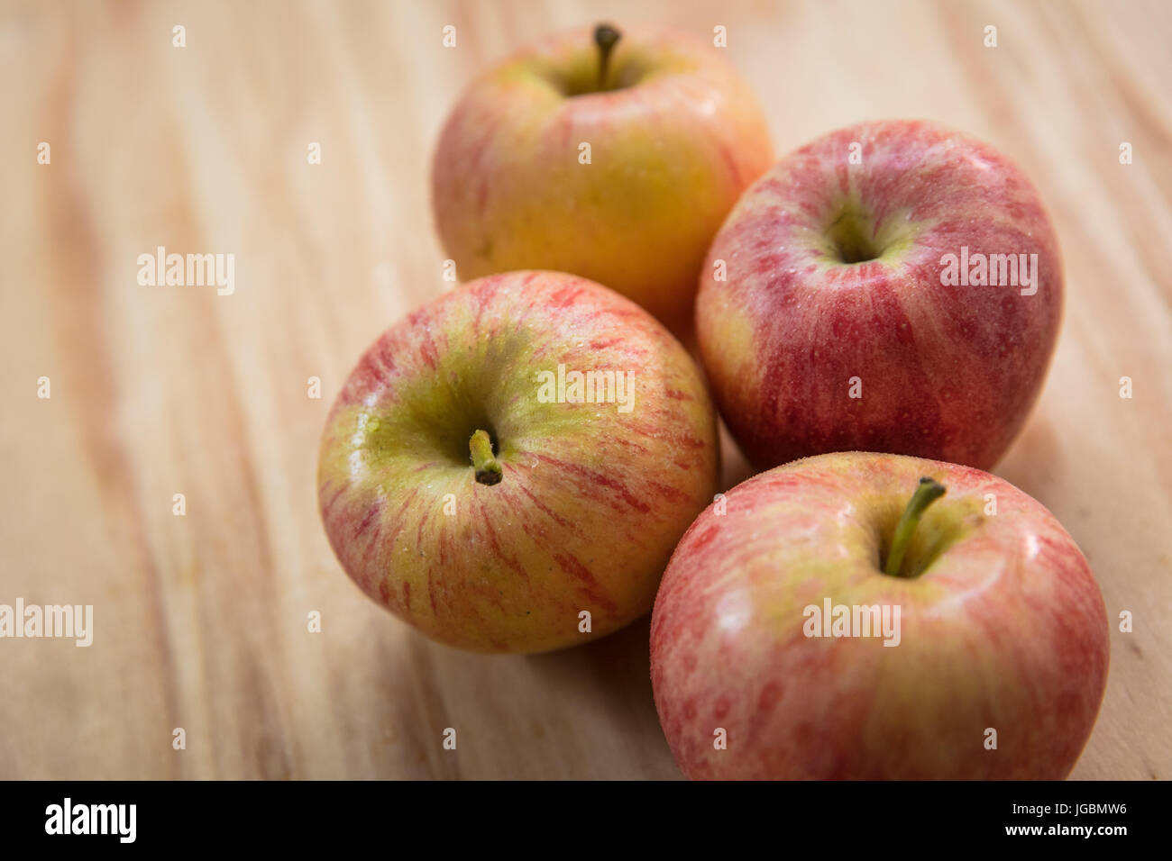 four apples on a wooden surface pink lady variety stock photo