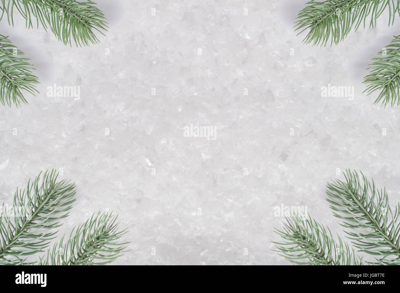 A background texture of artifical snow with ice fragments, framed by Christmas tree branches positioned in the corners. Stock Photo