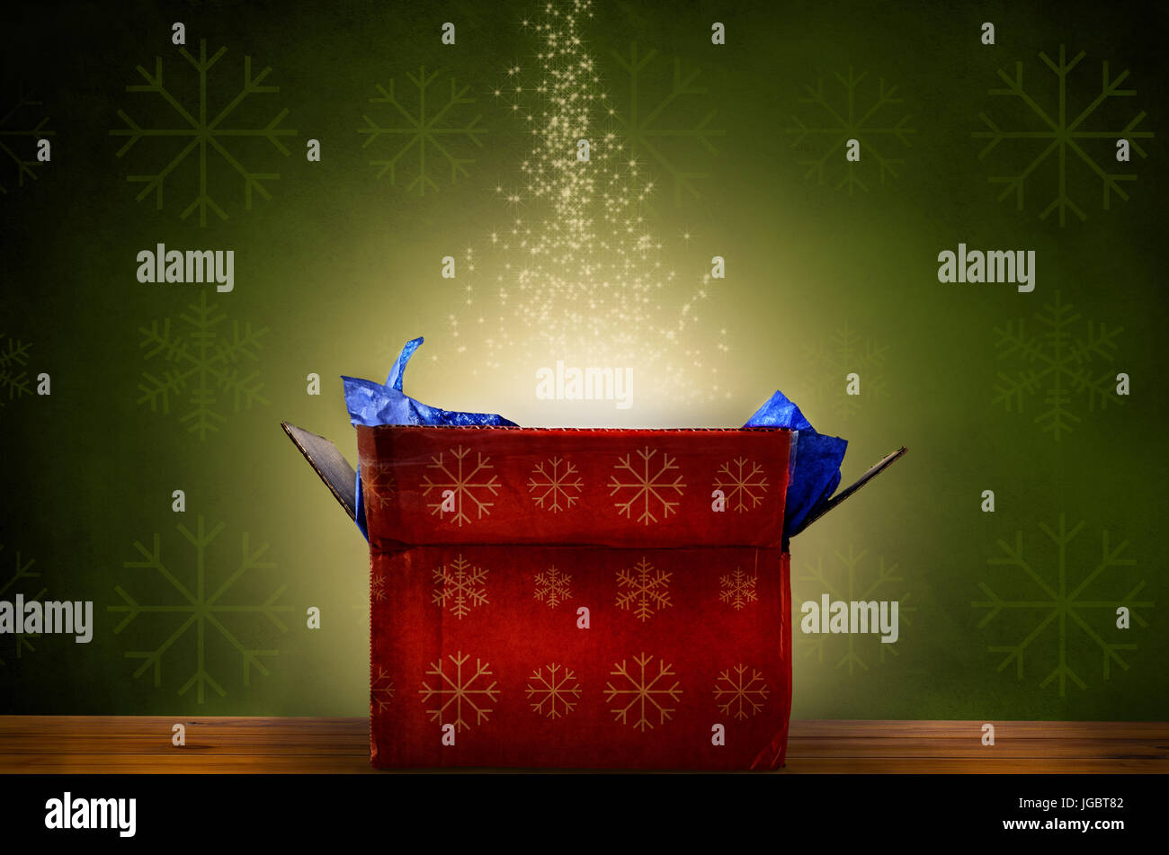 An opened red Christmas gift box with gold snowflake patterns, emitting a magical warm bright glowing light and rising sparkling stars.  Set against a Stock Photo
