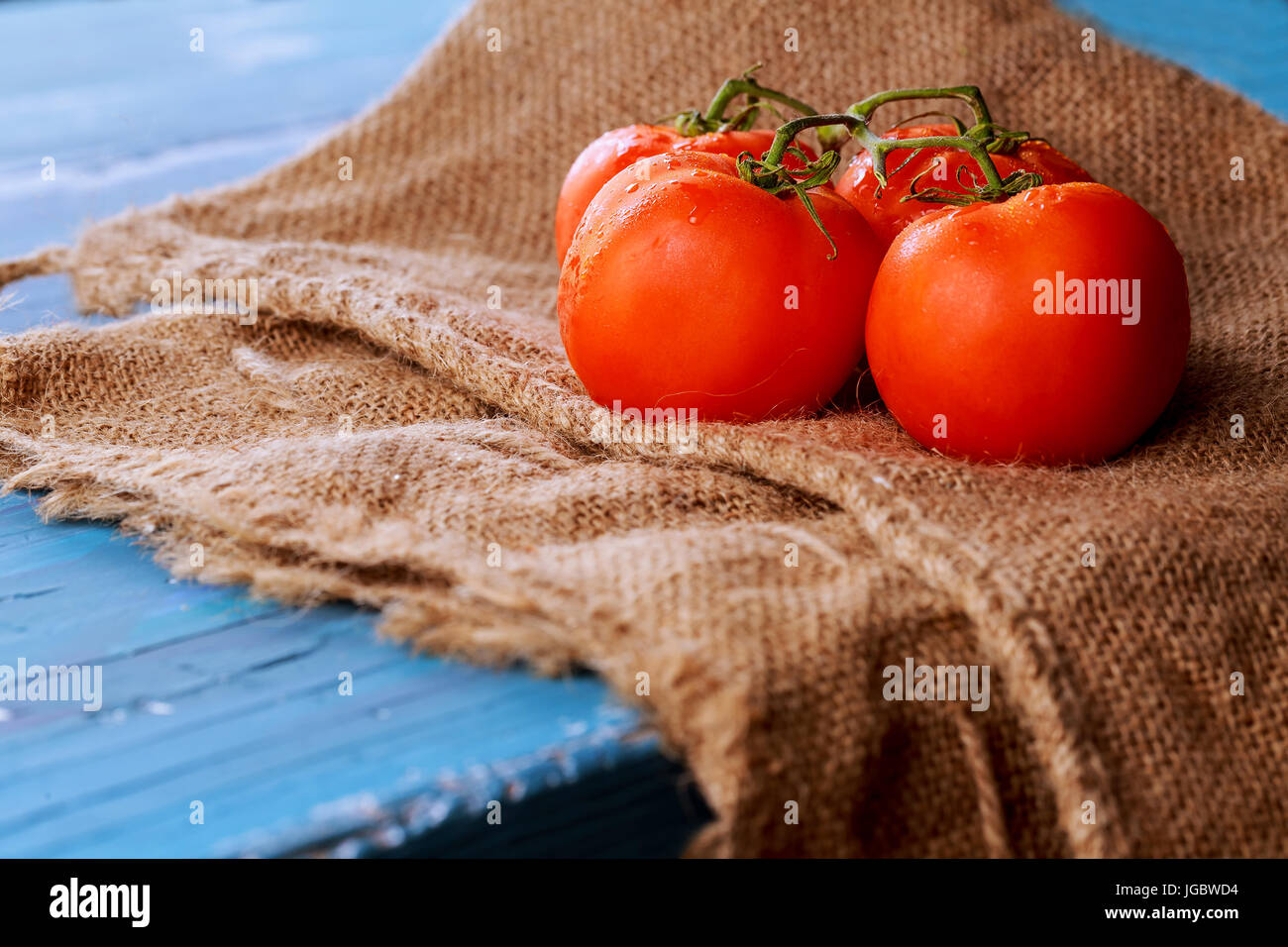 Tomatoes on vine with clipping path on cutting board , blue vintage wooden background, healthy lifestyle, cooking and market concept Stock Photo